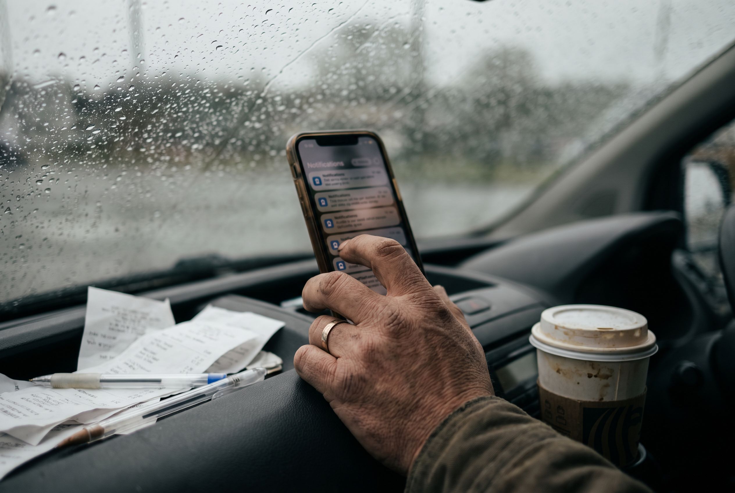 A tradesman in his van scrolling through a list of lead notifications on his phone